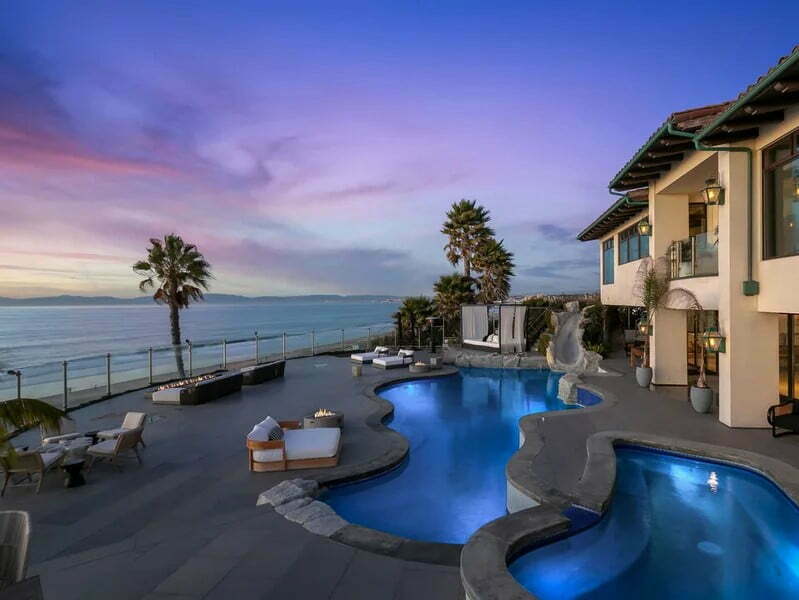 A pool with a view of the ocean and palm trees.