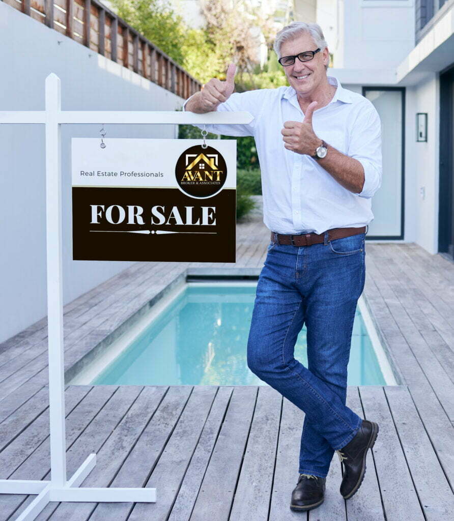 A man standing in front of a house with his thumbs up.