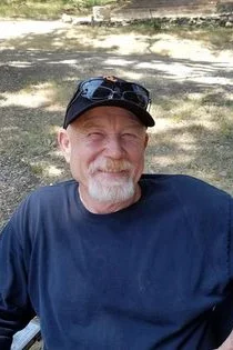 A man with a beard and hat is smiling.