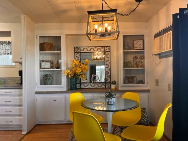 A dining room with yellow chairs and a glass table.