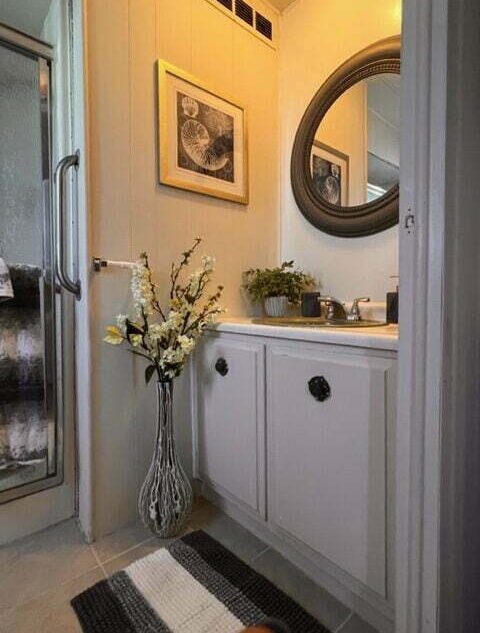 A bathroom with a vase of flowers and a mirror.